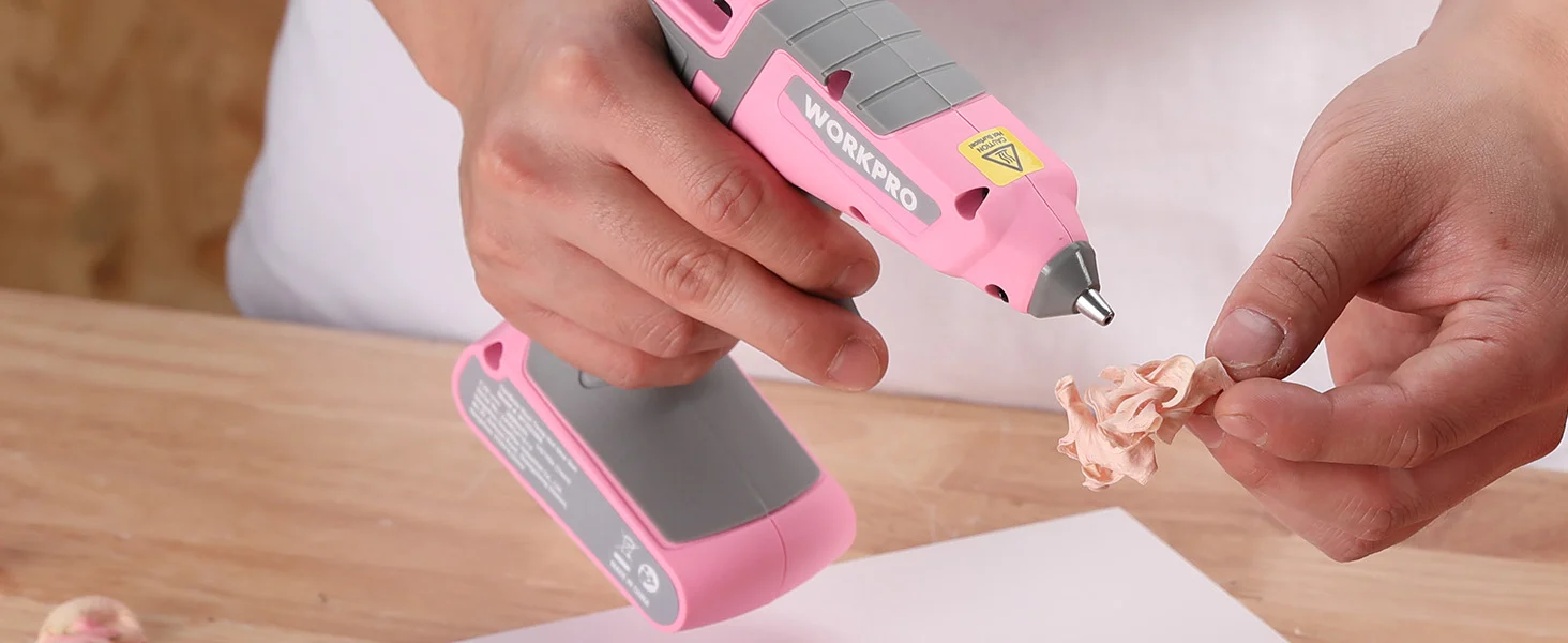 Hands using a pink Workpro tool to carve a small wooden figurine, showing innovation and quality craftsmanship