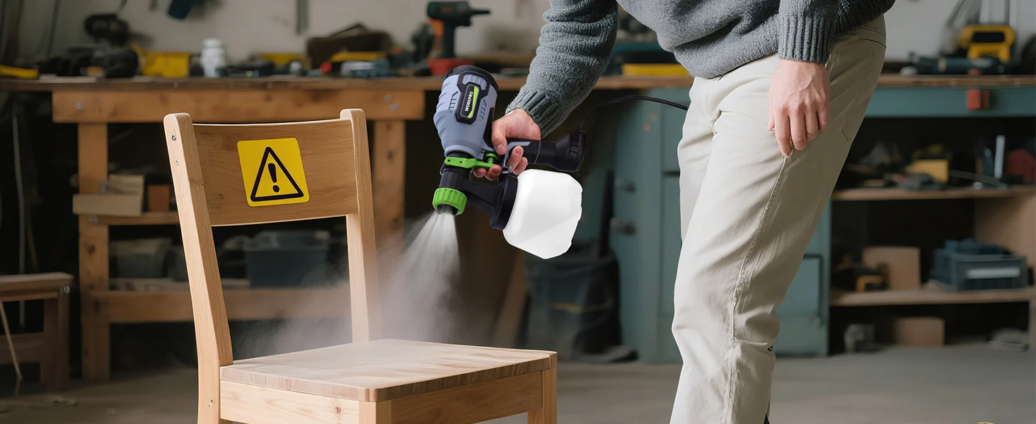 A worker uses a power tool to sand a wooden chair in a workshop, with dust cloud and caution sign