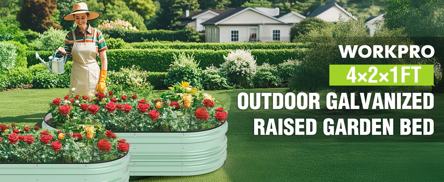 Raised garden bed with red and yellow flowers in a green yard, with a gardener watering and a house in back