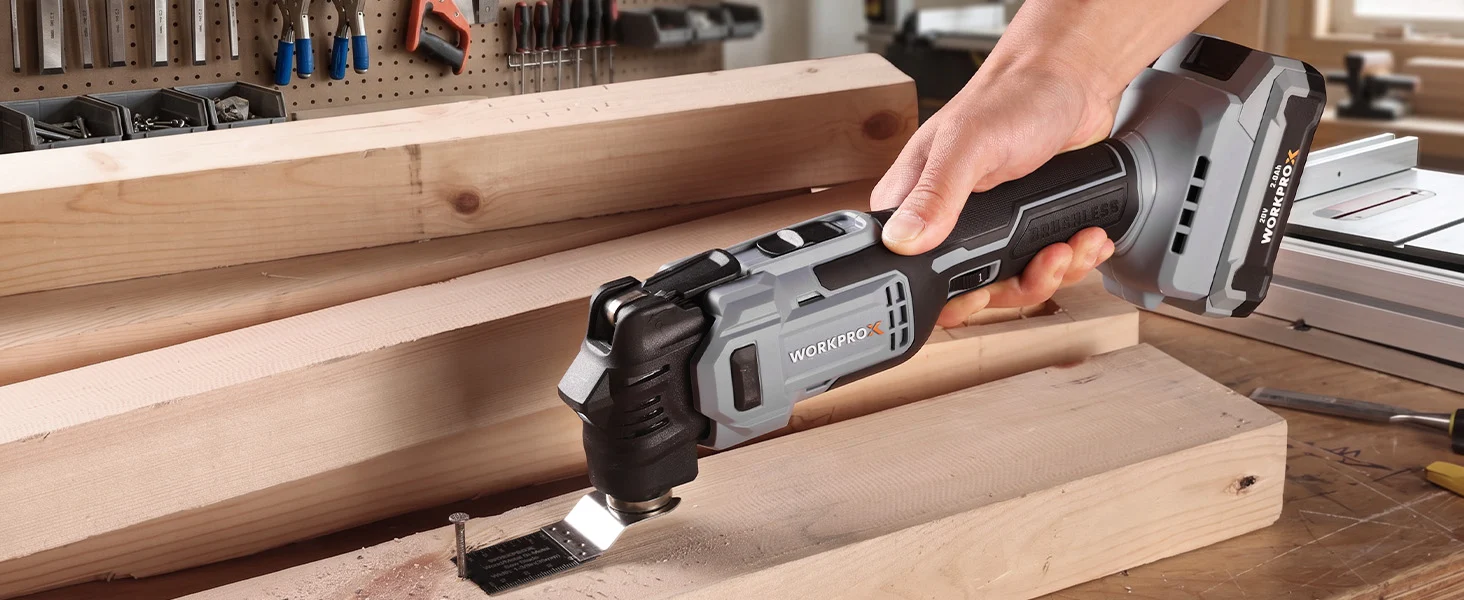 Hand holding a cordless power tool cutting wood on a workbench with visible workshop tools in the background
