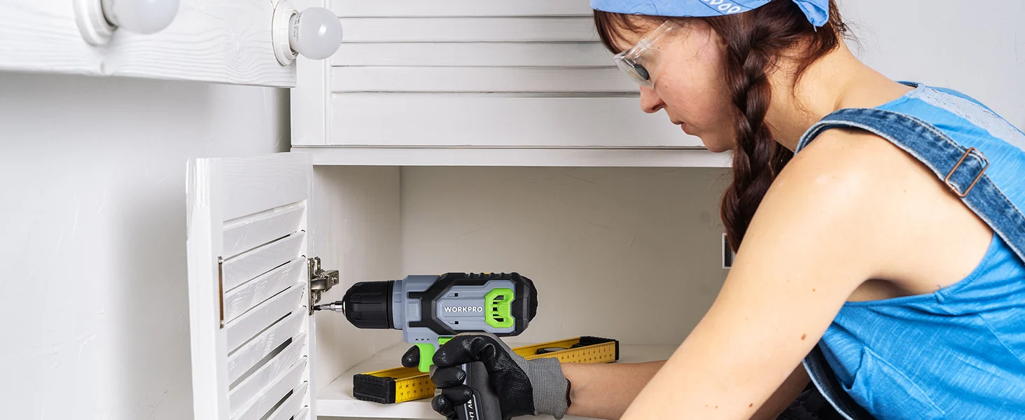 Woman installing a cabinet door with a cordless drill, showing innovation and quality in a home workshop