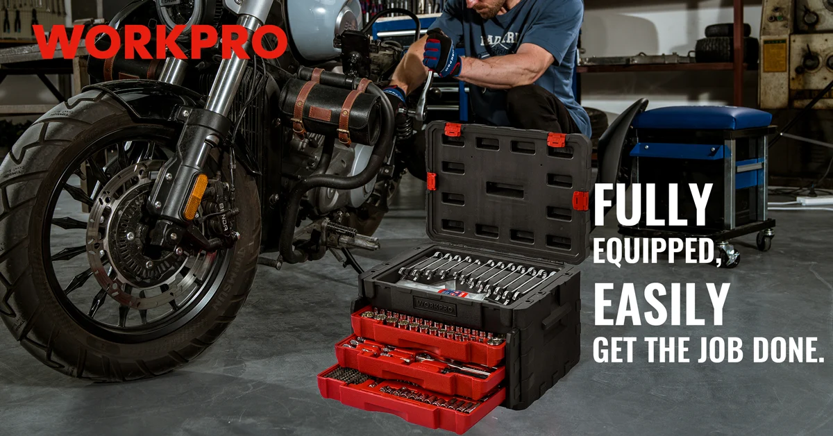 Mechanic in a workshop installing a motorcycle wheel, with a tool kit and screwdriver set on the floor