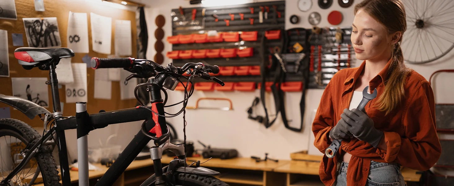 Mechanic in a workshop holding a wrench near a black bicycle, with innovation and quality tools in the background