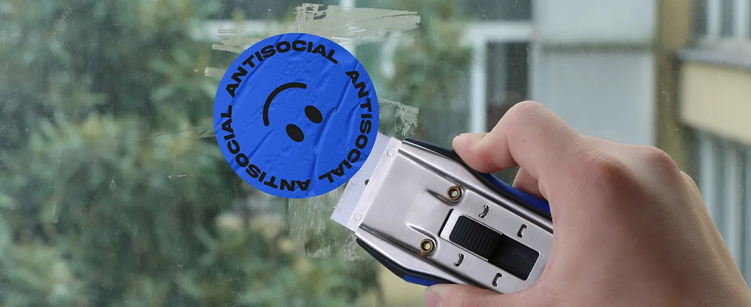 Hand holds a metal window latch with a blue innovation quality secure durable sticker on glass