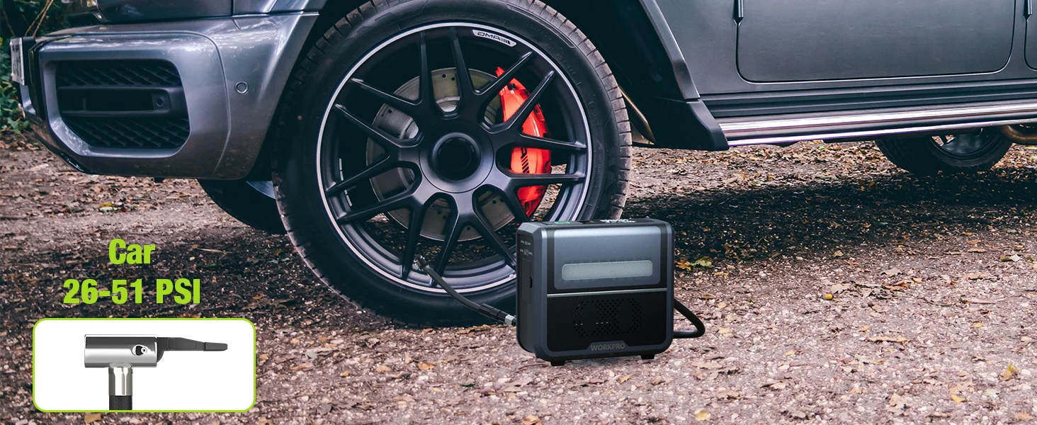 Car tire inflator gauge showing 26-51 PSI beside a wheel with red brake calipers on gravel ground