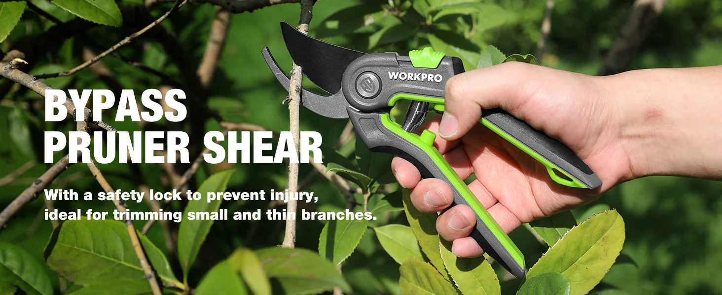 Hand holding a Workpro bypass pruner shear with green handles in a garden, shown for trimming branches