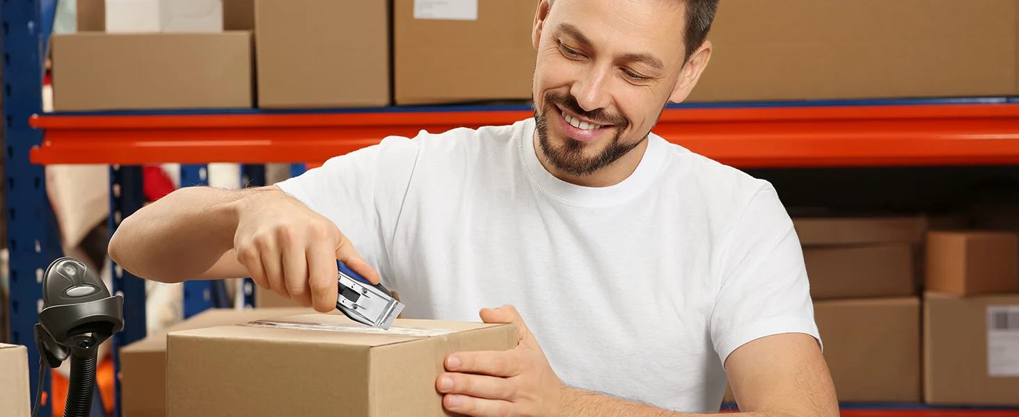 Warehouse worker smiling while installing a monitor bracket on a cardboard box, with innovation and quality