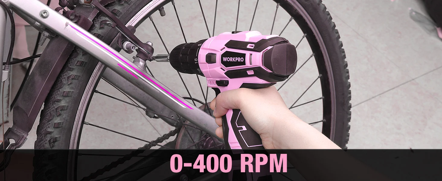 Hand holding a pink and black electric drill on a bicycle frame with WORKPRO branding and 0-400 RPM text