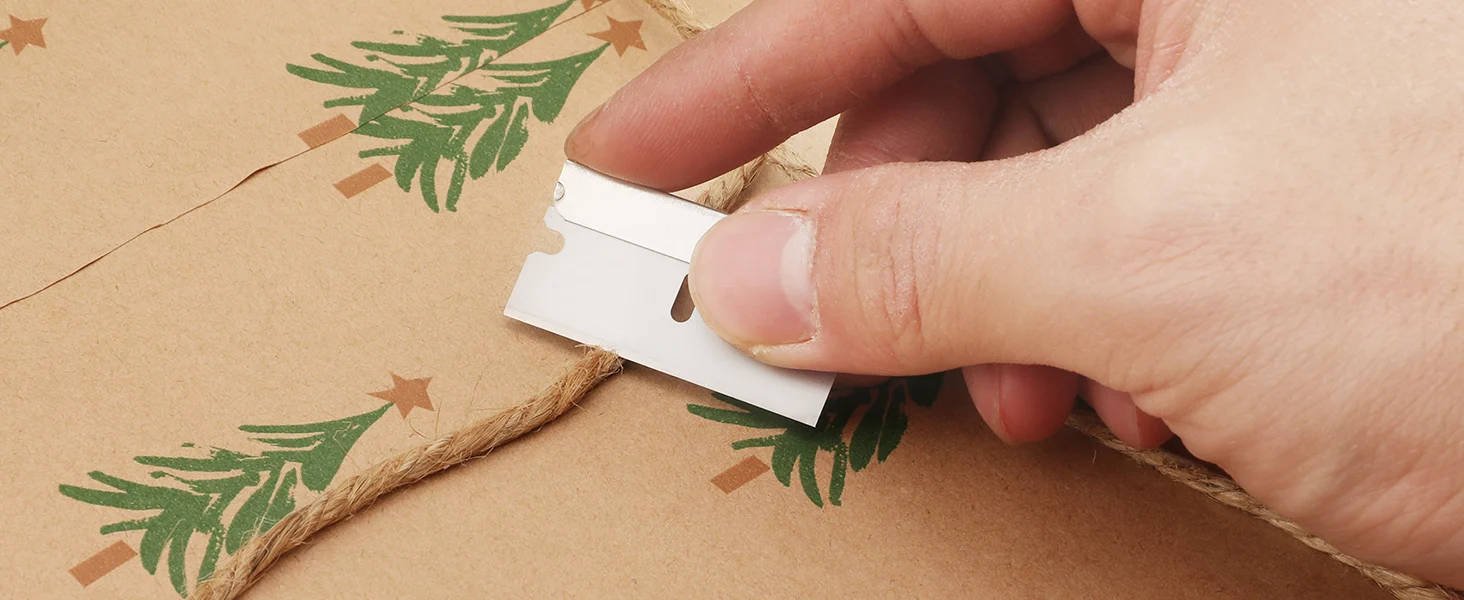 Hand pulling a white label tag from woven twine on kraft paper with green and brown star patterns