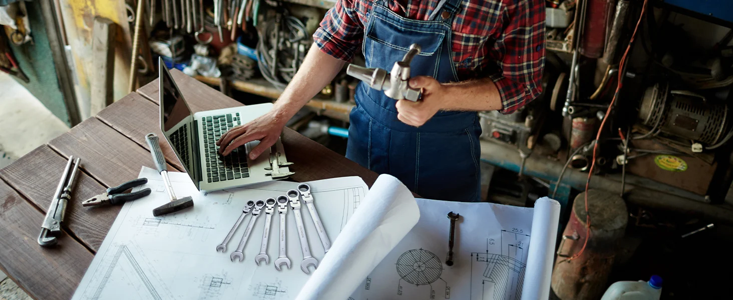 Workshop scene with innovation and quality, a mechanic using tools and an open laptop on a workbench