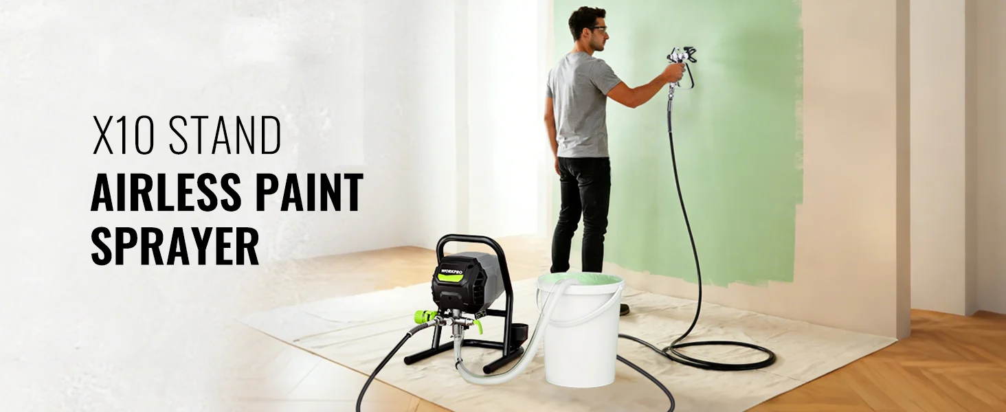 Airless paint sprayer with a painter applying green wall paint indoors on a drop cloth, with bucket and hose