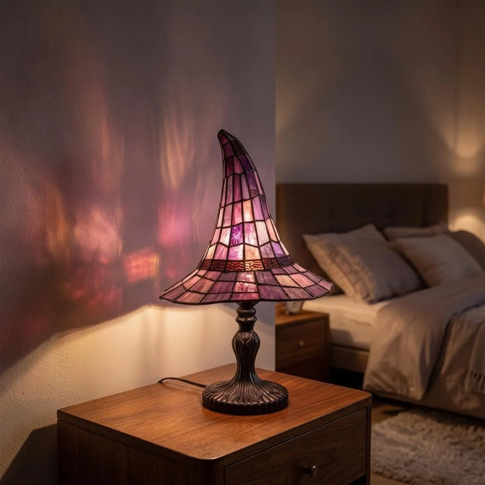 Stained glass table lamp lit on a nightstand, casting colored light on the wall