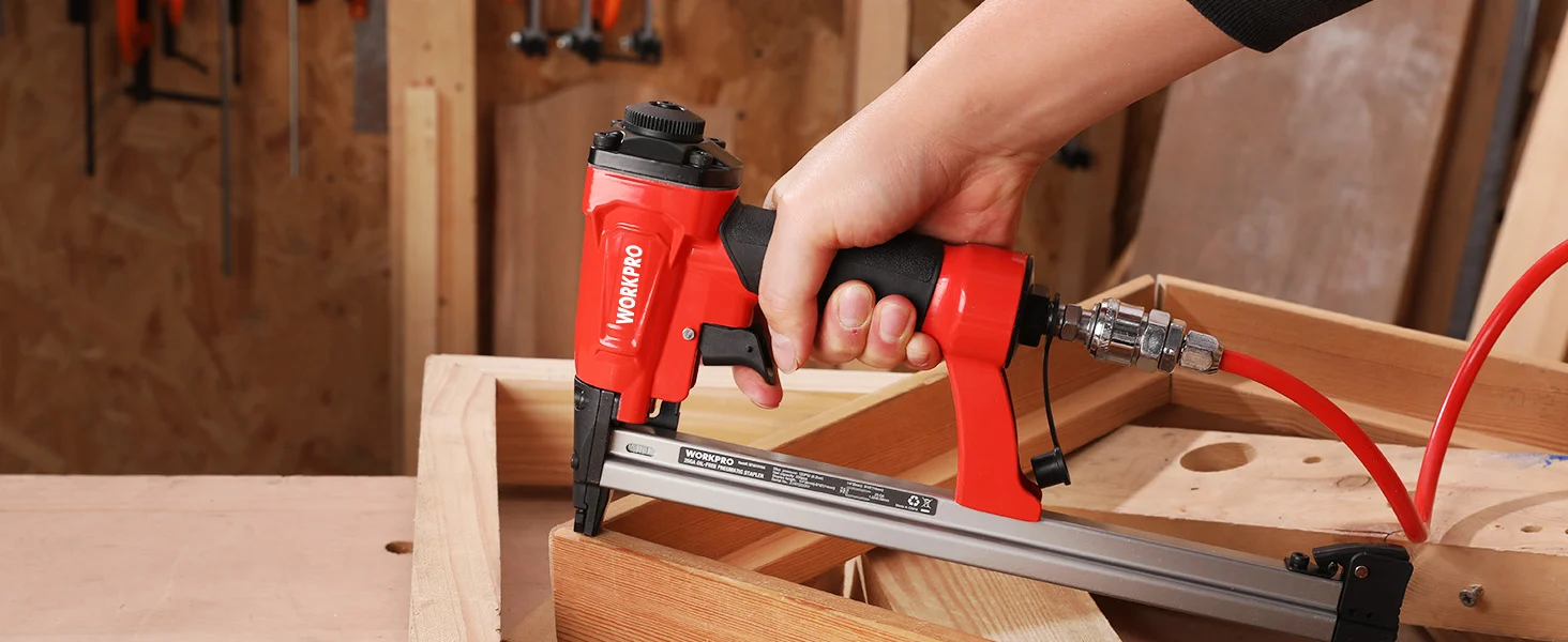 Hand holding a red nail gun innovation and quality tools, securing wooden boards in a workshop