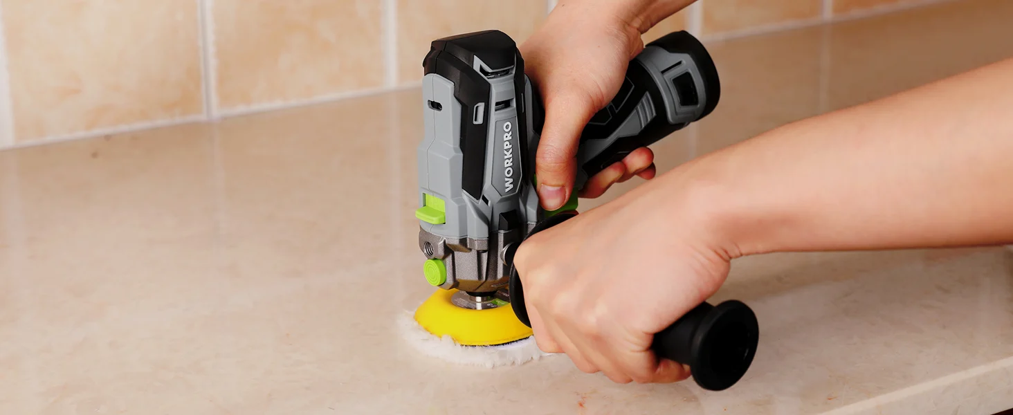 Hand using a power tool to polish a tile floor edge, with foam pad and bright yellow backing