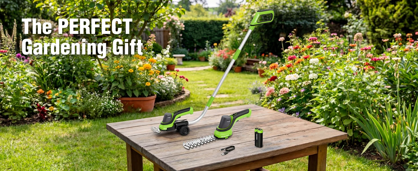 Garden tools with a green cordless trimmer and battery on a wooden table in a flower filled yard