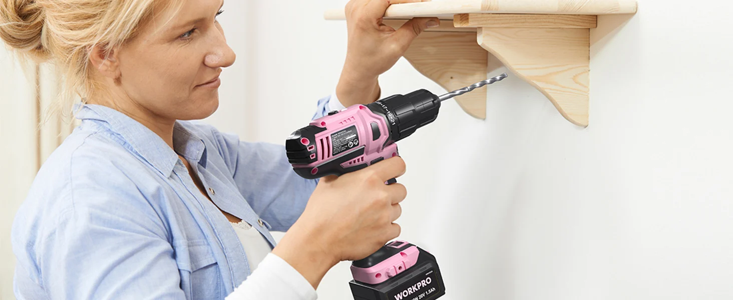 Woman using a pink and black power drill to install a wooden shelf, showing innovation and quality in home repair