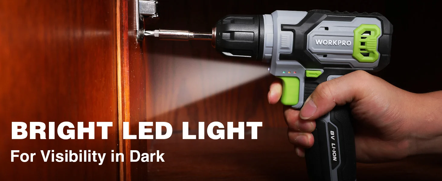Hand holding a Workpro cordless drill with a bit in a wooden door, with bright light for dark visibility